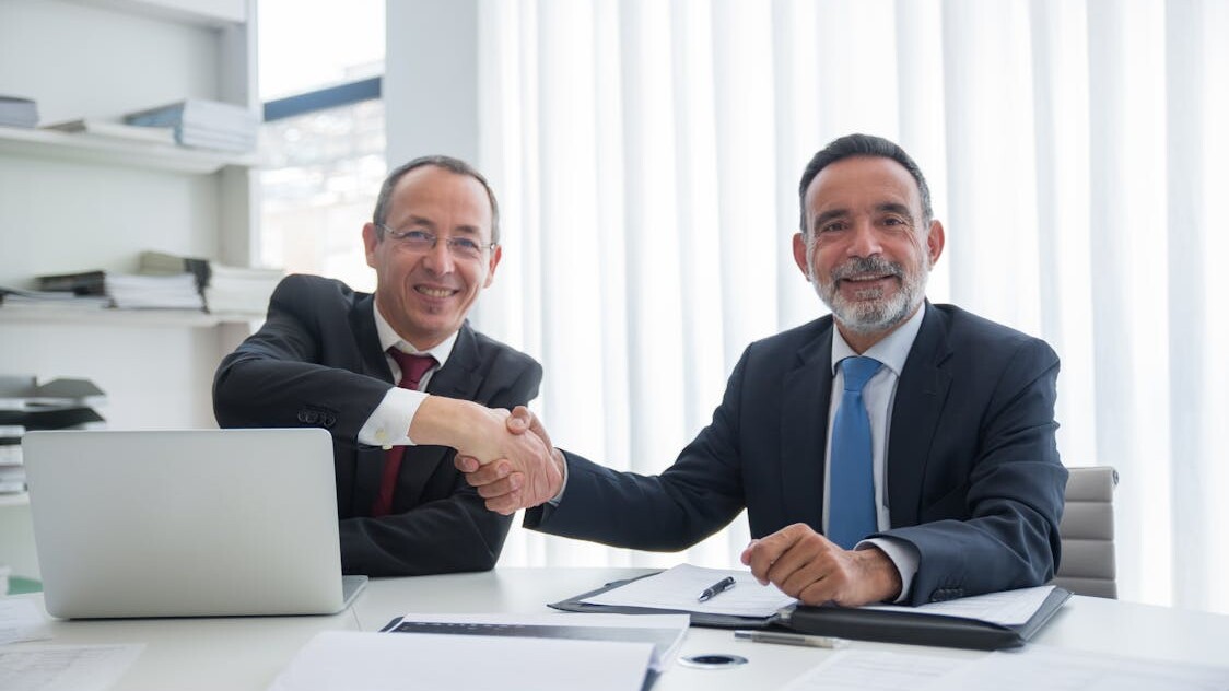 Two business professionals shaking hands over a succession agreement