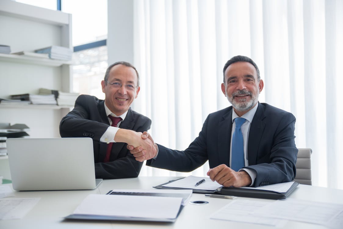 Two business professionals shaking hands over a succession agreement